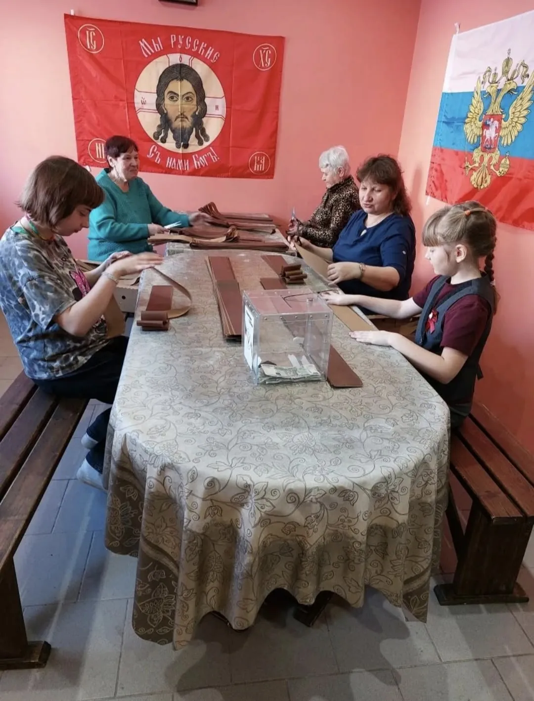 Рассказ о ежедневной работе женщин-волонтёров в две смены. Они вплетают в сети ленточки с псалмом. Получены ленточки и банки от Успенского храма.